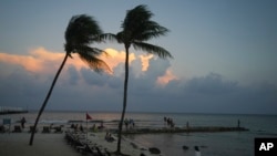 Gente en la playa mientras se pone el sol antes de la llegada del huracán Beryl en Playa del Carmen, México, el miércoles 3 de julio de 2024. 