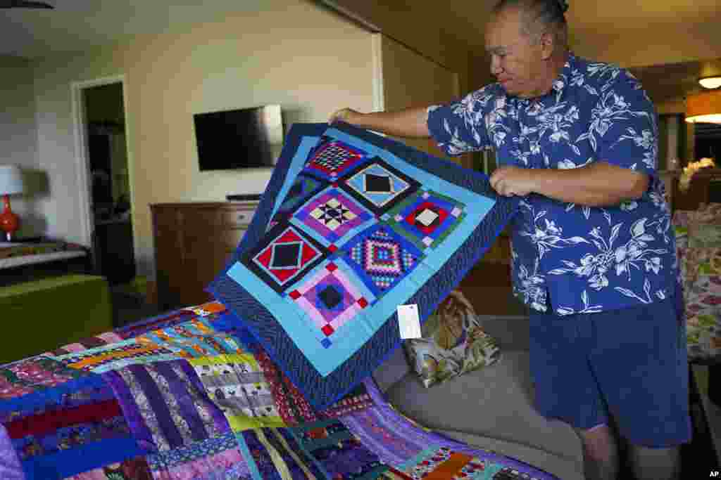 Charles Nahale lays the quilts gifted by his clients after the wildfire on Oct. 10, 2023, in Lahaina, Hawaii. 