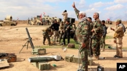 Soldados iraquís y voluntarios se preparan para lanzar morteros a las posiciones del grupo Estado islámico en las afueras de Tikrit. 