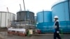  Seorang pekerja berjalan melewati tangki-tangki penyimpanan air yang terkontaminasi di pembangkit listrik tenaga nuklir Fukushima Dai-ichi yang lumpuh akibat bencana tsunami, milik Tokyo Electric Power Co. di Kota Okuma, Prefektur Fukushima, 23 Februari 2017.