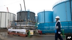  Seorang pekerja berjalan melewati tangki-tangki penyimpanan air yang terkontaminasi di pembangkit listrik tenaga nuklir Fukushima Dai-ichi yang lumpuh akibat bencana tsunami, milik Tokyo Electric Power Co. di Kota Okuma, Prefektur Fukushima, 23 Februari 2017.