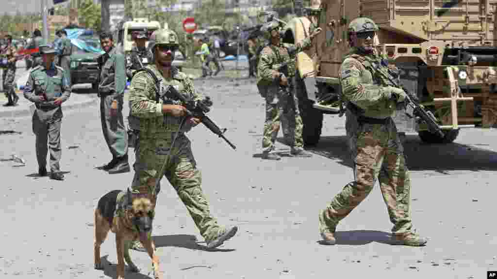 NATO and Afghan security forces walk at the site of a suicide attack in Kabul, Afghanistan, Aug. 10, 2014.