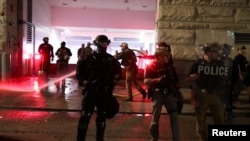Agentes federales apagan un incendio en medio de manifestaciones en el edificio de la Corte Federal en Portland, Oregón.