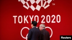 Presiden Komite Olimpiade Internasional (IOC) Thomas Bach berjalan bersama PM Jepang Shinzo Abe dalam upacara 'One Year to Go' menjelang pelaksaan Olimpiade Musim Panas Tokyo 2020. (Foto: dok). 