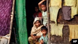 A Burmese Muslim family, who identify themselves as long-persecuted “Rohingya” Muslims, look out from their tents at Da Paing camp for Muslim refugees in north of Sittwe, Rakhine State, western Burma, April 2, 2014. 