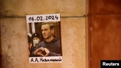 En la toma, una foto del líder opositor ruso Alexei Navalny pegada en una pared mientras la gente asiste a una vigilia tras su muerte en el Trocadero cerca de la Torre Eiffel en París, Francia, el 19 de febrero de 2024.