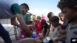 FILE - Displaced Palestinian children queue for food in a camp in Deir al-Balah, Gaza Strip, Oct. 18, 2024. 