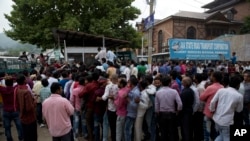 Indian migrant workers wait outside the government transport yard waiting to buy bus tickets to leave the region, during curfew in Srinagar, Indian controlled Kashmir, Aug. 7, 2019.