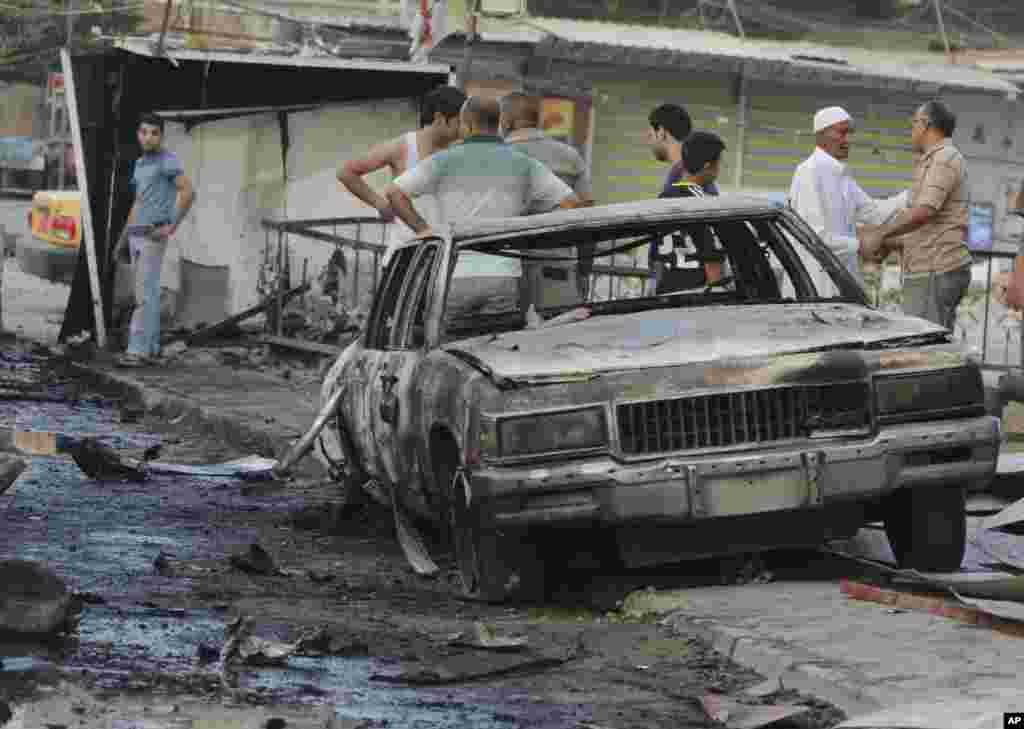 People inspect the aftermath of a car bomb explosion at a commercial street in Baghdad's eastern neighborhood of Mashtal, Sept. 16, 2013.