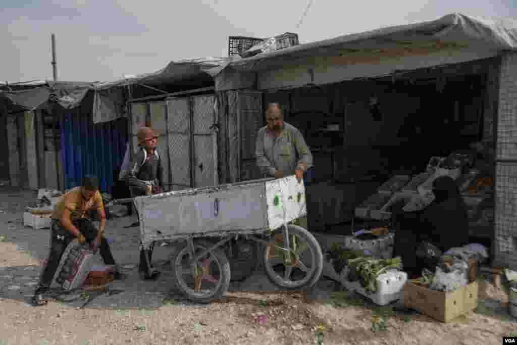A man and two young boys bring food and drinks to be sold in the market area of al-Hol Camp, the largest prison camp in Northeast Syria, on Oct. 12, 2024. (Diego Baravelli/VOA)