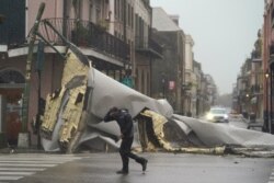 Un hombre pasa por una sección del techo que se desprendió de un edificio en el Barrio Francés por los vientos del huracán Ida, el domingo 29 de agosto de 2021, en Nueva Orleans.