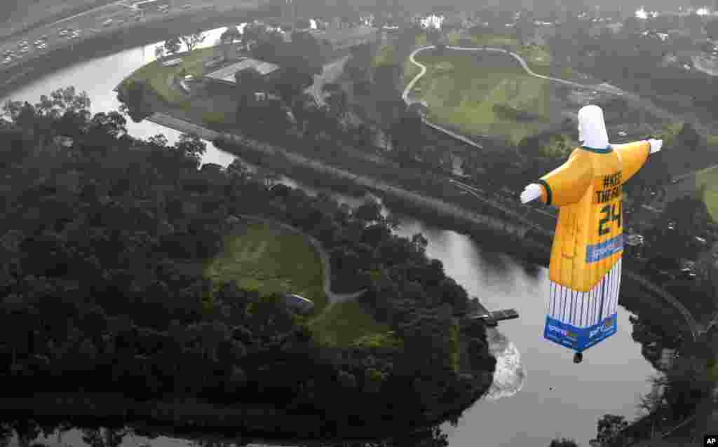 Sebuah balon udara yang berbentuk mirip patung Yesus (di kota Rio de Janeiro), yang mengenakan kostum timnas Australia terbang di atas kota Melbourne.