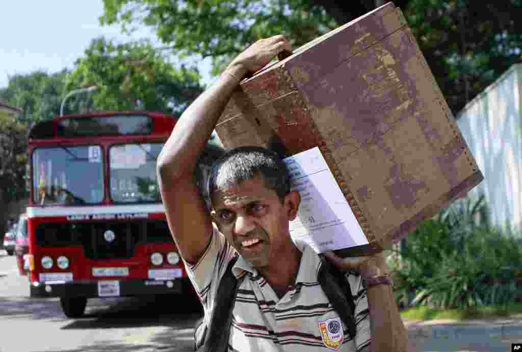 A Sri Lankan polling officer carries a ballot box towards a polling station on the eve of the presidential elections in Colombo, Sri Lanka, Jan. 7, 2015. 