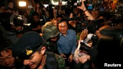 Mantan Menteri Pendidikan Thailand, Chaturon Chaisang (tengah), dikawal ketat oleh tentara dan dikerumuni oleh wartawan seusai memberikan sambutan di Klub Koresponden Asing di Bangkok, Thailand (27/5).