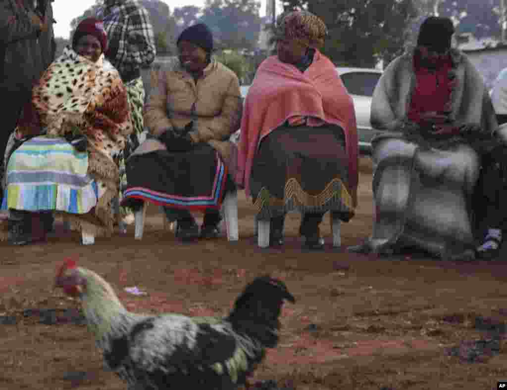 Para perempuan duduk dan mengantre giliran memberikan suara di sebuah pemukiman sementara di Soweto, Afrika Selatan (7/5). (AP/Denis Farrell)