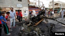 Warga berkumpul di lokasi ledakan bom bunuh diri di distrik Kamaliya, Baghdad, Senin (20/5). Serangan di Baghdad menewaskan sedikitnya 48 orang. 