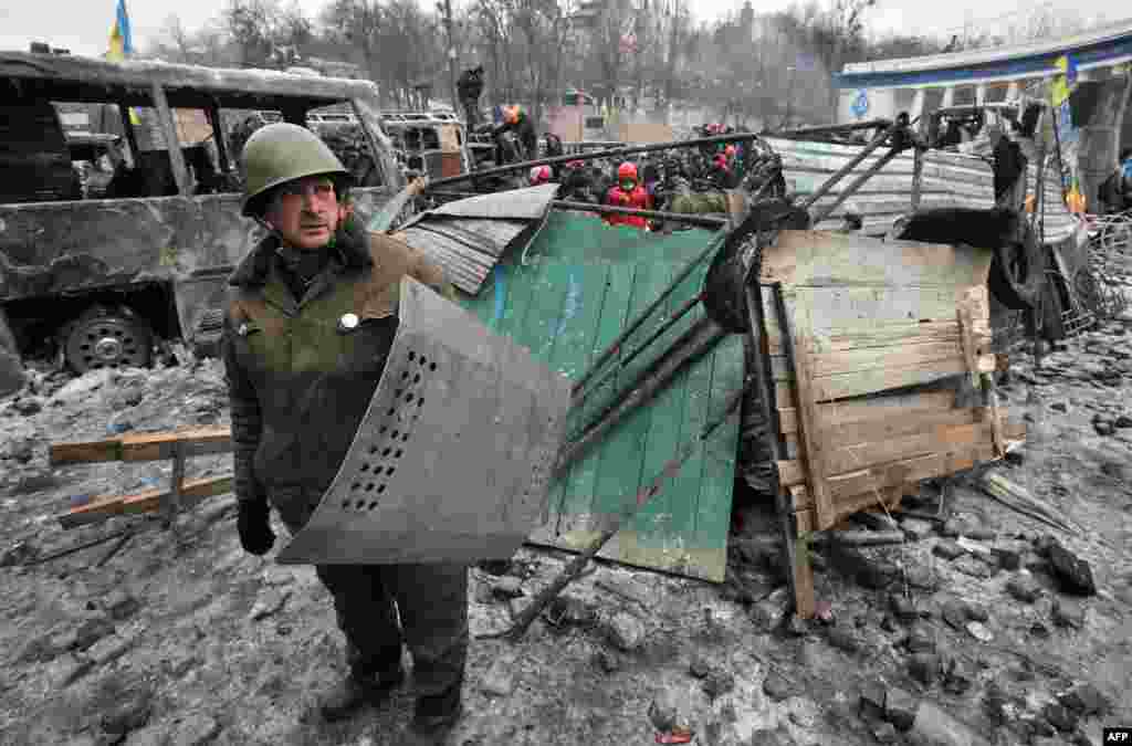 Seorang demonstran anti pemerintah memegang perisai milik polisi Ukraina setelah bentrokan antara demonstran dengan polisi di ibukota Kyiv, Ukraina.