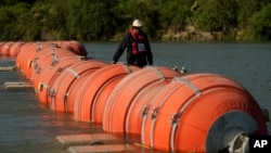 Una persona en kayak pasa al lado de boyas instaladas como barrera en el Río Grande, el 1 de agosto de 2023, en Eagle Pass, Texas, EEUU.