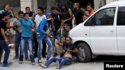 Warga Palestina mencoba mengevakuasi seorang pria yang terluka dalam bentrokan dengan pasukan Israel di pos pemeriksaan Qalandia dekat Ramallah, Tepi Barat (6/10). (Reuters/Mohamad Torokman)