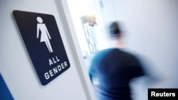 FILE - A bathroom sign welcomes both genders at the Cacao Cinnamon coffee shop in Durham, N.C., May 3, 2016.