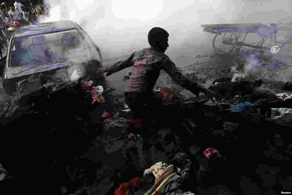 A boy tries to control a fire after vehicles were torched and vandalized by Jamaat-e-Islami party activists during clashes with police in Dhaka, Dec. 13, 2013.