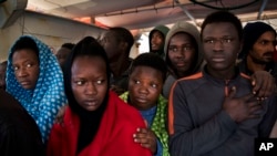 Migrants aboard the Golfo Azurro rescue vessel wait to be transferred to Italian authorities in Trapani harbor, on the Italian island of Sicily, Saturday, April 8, 2017.