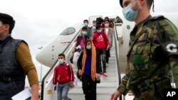 Siswa bersama anggota fakultas dari Institut Musik Afghanistan tiba di pangkalan udara militer Lisbon, Portugal, pada 13 Desember 2021. Mereka mendapatkan suaka dari pemerintah Portugal. (Foto: AP/Armando Franca)