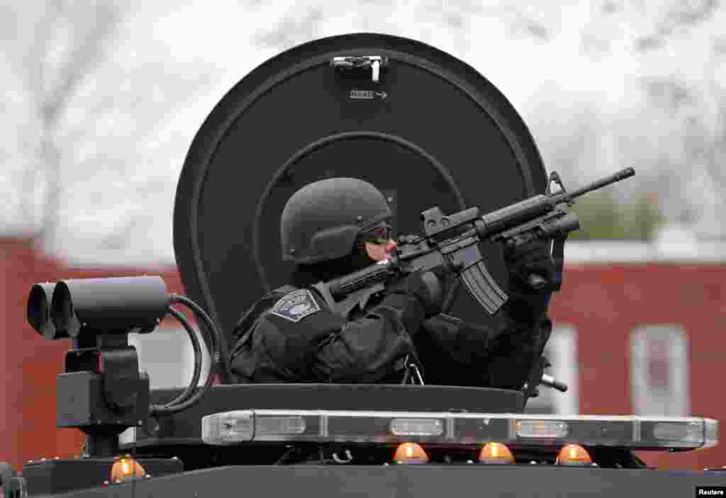 Un miembro del equipo SWAT dirige su arma contra uno de los edificios del vecindario en Watertown durante la búsqueda del sospechoso.