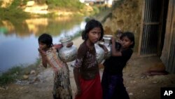 FILE - Rohingya girls carry water pots at Kutupalong refugee camp, in Cox's Bazar, Bangladesh, Nov. 19, 2017.