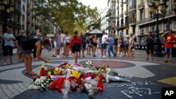 巴塞罗那历史悠久的兰布拉大道(Las Ramblas)上，一名女子在纪念仪式周围放了一朵花，悼念2017年恐怖袭击的遇难者。(2018年8月16日)