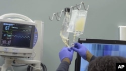 In this January 2019 image made from video provided by Penn Medicine, IV bags of CRISPR-edited T cells are prepared for administering to a patient at the Abramson Cancer Center in Philadelphia. (Penn Medicine via AP)