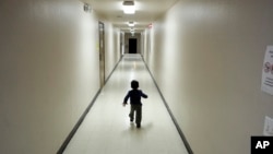 FILE - An asylum-seeking boy from Central America runs down a hallway after arriving from an immigration detention center to a shelter in San Diego, Dec. 11, 2018.