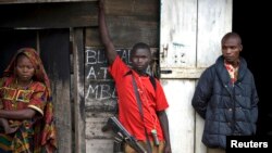 FILE - Congolese fighters from the Mai-Mai militia stand outside a hut in the village of Kalenge in eastern Congo, Feb. 4, 2009. 