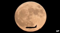 A jet plane flies across the moon seen from Beijing, China, Nov. 14, 2016. The brightest moon in almost 69 years lights up the sky on Monday in a treat for star watchers around the globe. 