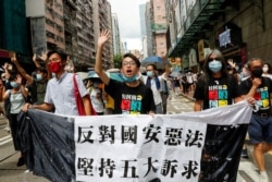 FILE- (L-R) Pan-democratic legislator Eddie Chu Hoi-dick, Vice convener for Hong Kong's Civil Human Rights Front Figo Chan, and activist Leung Kwok-hung, march at the anniversary of Hong Kong's handover to China from Britain, Hong Kong, July 1, 2020.