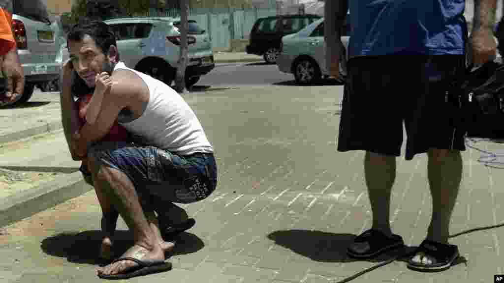 An Israeli hugs his child outside a shelter as a siren warning of incoming rockets is heard around the southern city of Beersheba, Israel, July 12, 2014.