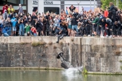FILE - The statue of 17th century slave trader Edward Colston falls into the water after protesters pulled it down during a protest against racial inequality, in Bristol, Britain, June 7, 2020.