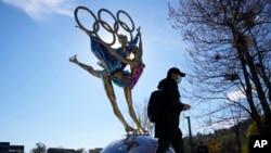 Seorang pengunjung Taman Shougang, Beijing, berjalan melewati patung yang menggambarkan perhelatan Olimpiade Musim Dingin Beijing 2022, pada 9 November 2021. AS telah mengumumkan boikot diplomatik terhadap perhelatan tersebut. (Foto: AP/Ng Han Guan)