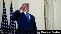 FILE PHOTO: U.S. President Donald Trump poses without face mask as he returns to the White House after being hospitalized at Walter Reed Medical Center for coronavirus disease (COVID-19), in Washington