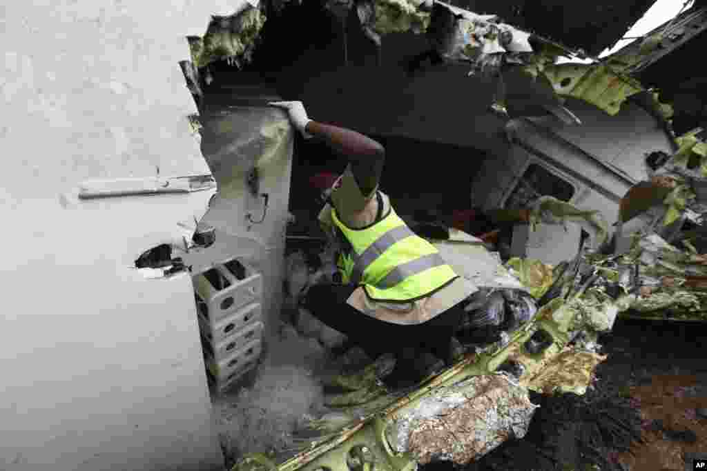 A rescue worker inspects the wreckage of a charter passenger jet that crashed soon after take off from Lagos airport, Nigeria, Oct. 3, 2013.