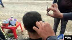Abdullah, cutting this man's hair, does not want his face on camera for fear of IS reprisal attacks on his family inside Mosul. Refugees consistently report that their families fear death if relatives who fled talk to journalists, at the Khazir camp in Kurdish Iraq, Dec. 13, 2016. (H. Murdock/VOA)