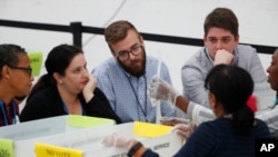 Empleados de la oficina del Supervisor de Elecciones del condado de Broward realizan el recuento manual en presencia de observadores del Partido Demócrata y Republicano.