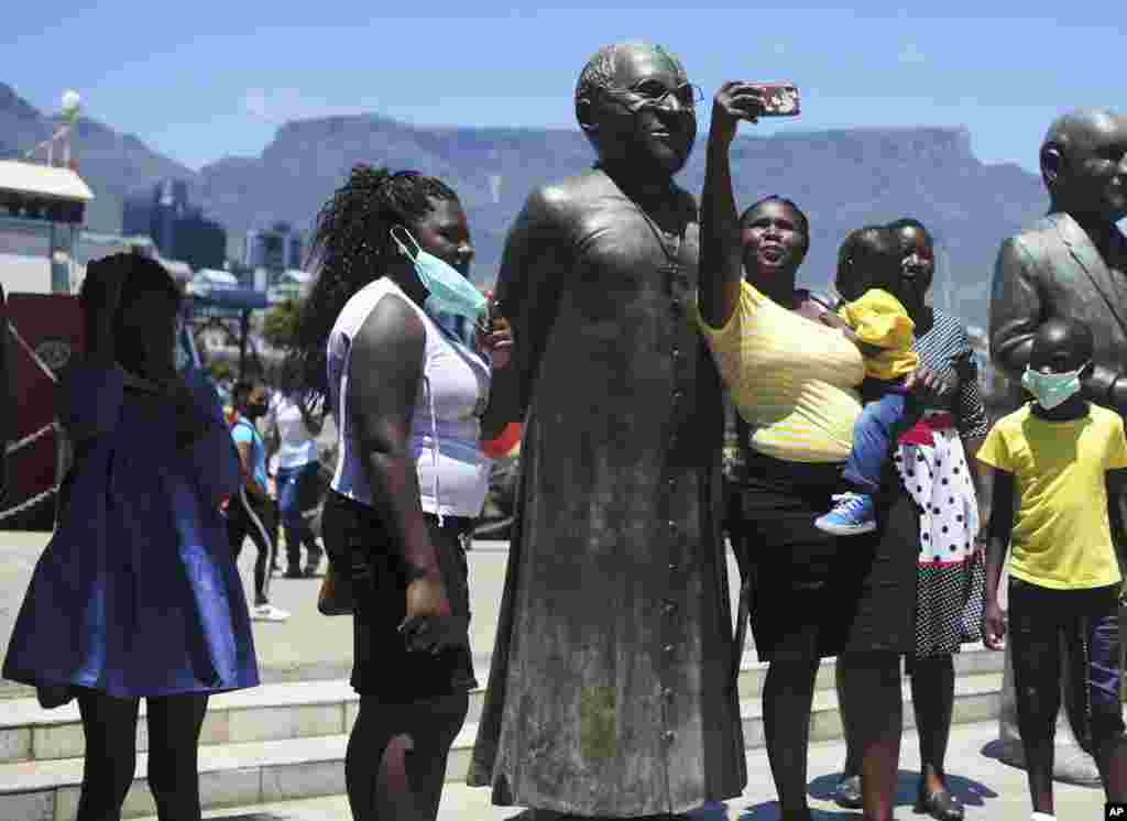 People take photos at a statue of Anglican Archbishop Desmond Tutu at the V&A Waterfront in Cape Town, South Africa. South Africa's president says Tutu, the country's Nobel Peace Prize-winning activist for racial justice and LGBT rights and the retired Anglican Archbishop of Cape Town, has died at the age of 90.