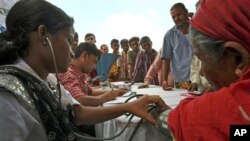 A health worker of a private hospital checks the blood pressure of a slum dweller as others wait at a roadside health camp in Dhaka, Bangladesh, Aug. 5, 2010.