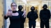 FILE - Opposition activist Lyubov Sobol reports live by phone as policemen stand guard during a raid at offices of the Anti-Corruption Foundation, in Moscow, Russia, Dec. 26, 2019. The foundation was established by prominent Kremlin critic Alexei Navalny.