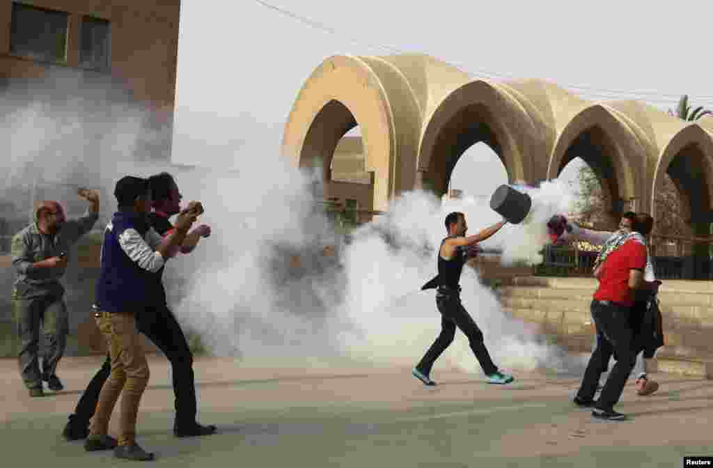 A man uses a bucket to put out a tear gas canister as Coptic Christians run inside the Saint Mark Coptic cathedral during clashes with Muslims, April 7, 2013.