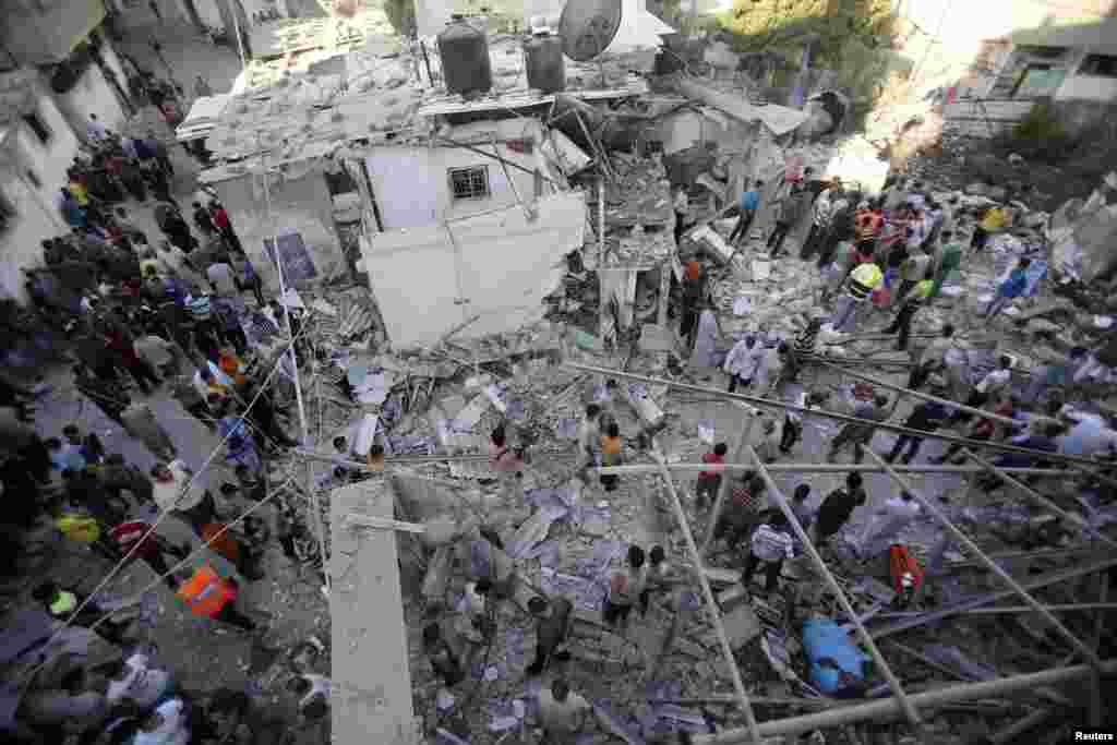 Rescue workers search for victims as Palestinians gather around the wreckage of a house, which witnesses said was destroyed in an Israeli airstrike that killed at least nine members from the al-Ghol family, in Rafah, southern Gaza Strip, August 3, 2014.