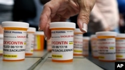 Family and friends who have lost loved ones to OxyContin and opioid overdoses leave pill bottles in protest outside the headquarters of Purdue Pharma, which is owned by the Sackler family, in Stamford, Conn., Aug. 17, 2018.