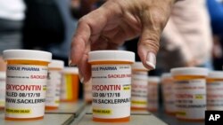 Family and friends who have lost loved ones to OxyContin and opioid overdoses leave pill bottles in protest outside the headquarters of Purdue Pharma, which is owned by the Sackler family, in Stamford, Conn., Aug. 17, 2018.