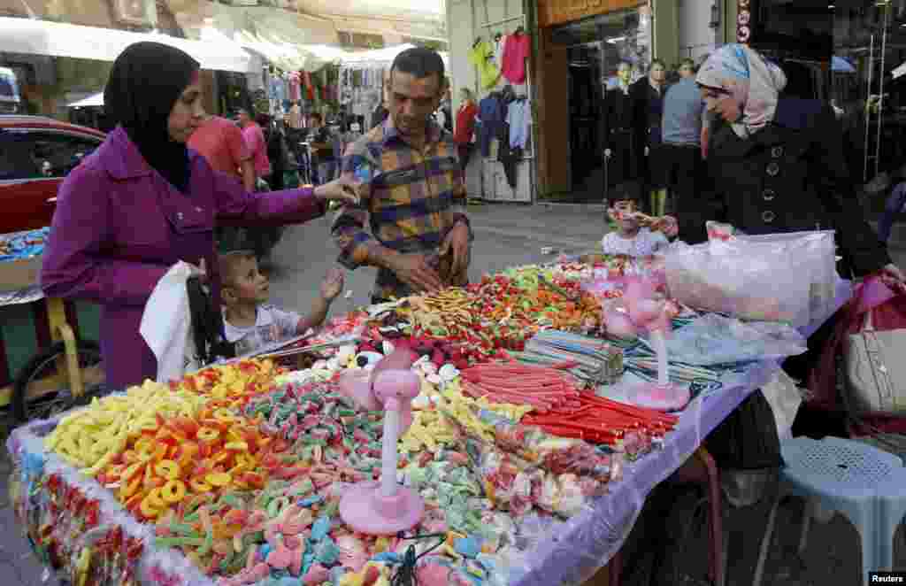 Palestinian customers buy candies from a vendor at a shop in the old market ahead of the Eid al-Adha festival, in the West Bank city of Nablus, Sept. 23, 2015.
